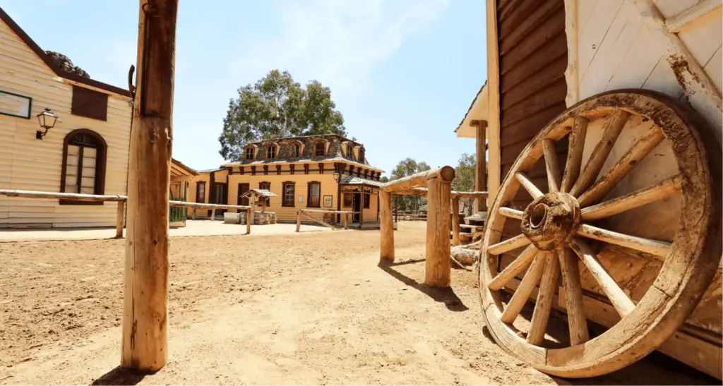 Wild West town movie set with wooden buildings and a large wagon wheel