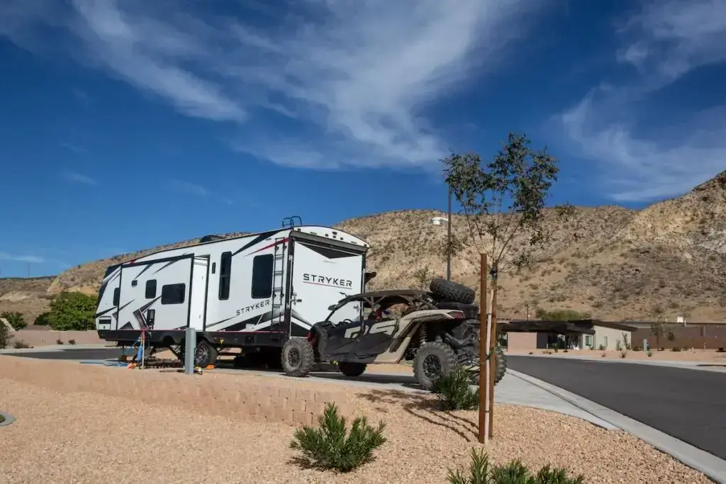 Stryker travel trailer and off-road vehicle at a desert campsite.