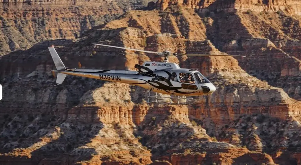 A Zion Helicopters tour flight soaring past the rugged red rock cliffs and plateaus of Zion National Park