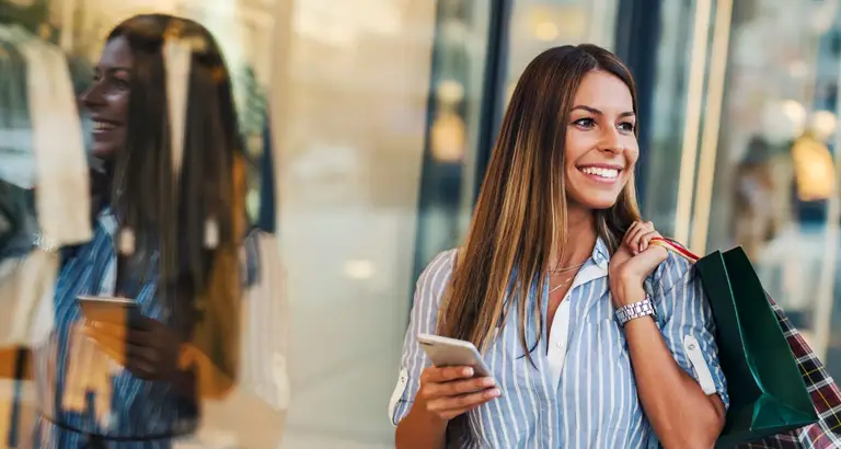 Happy customer shopping at a retail boutique with mobile phone.