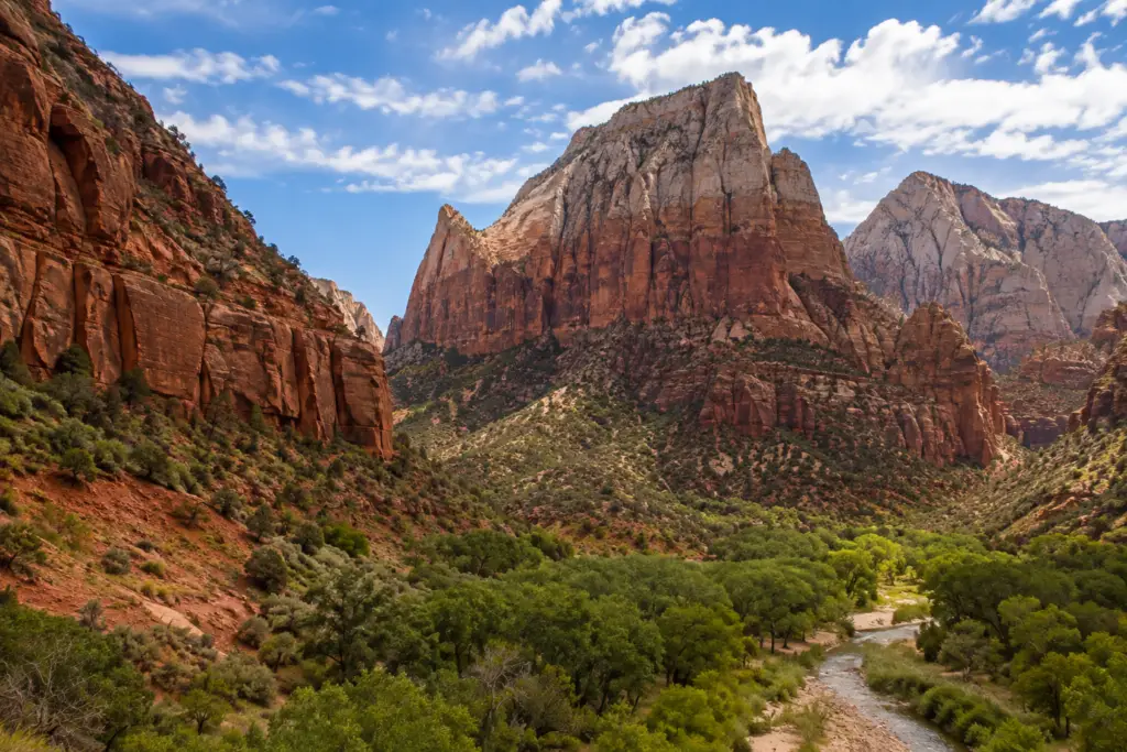 Zion National Park canyon with towering red sandstone cliffs, green valley.