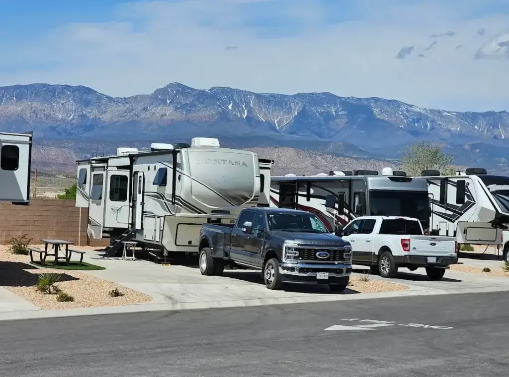 Long-term RV park in Utah with a fifth-wheel RV and pickup truck surrounded by desert landscaping and mountain views
